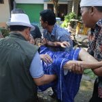 Doc.Dr. H. Dian Rachmat Yanuar, M.Si. sedang ikut mengangkat Sahrun (75) hidup sebatang kara (Foto Dokumentasi : MI)