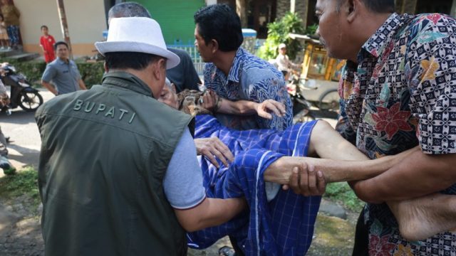 Doc.Dr. H. Dian Rachmat Yanuar, M.Si. sedang ikut mengangkat Sahrun (75) hidup sebatang kara (Foto Dokumentasi : MI) bupati