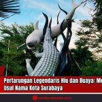 Doc. Patung ikonik Hiu dan Buaya di tengah kota Surabaya tampak menjulang di antara rimbunnya pepohonan, menjadi simbol legendaris asal-usul nama kota Surabaya. Patung ini menggambarkan pertarungan sengit antara Hiu Sura dan Buaya Baya, dua makhluk mitologis yang konon berebut wilayah kekuasaan lautan dan daratan. Kisah ini merupakan bagian dari cerita rakyat Jawa Timur yang terus dilestarikan dan menjadi identitas budaya serta kebanggaan masyarakat Surabaya. Patung tersebut kini menjadi salah satu destinasi wisata dan latar edukatif yang memperkenalkan nilai-nilai seperti kejujuran, keberanian, dan konsekuensi dari pengkhianatan. (Doc: SandiWartaNews.com).